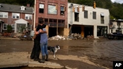 Resident Anne Schneider, right, hugs her friend Eddy Sampson as they survey damage left in the wake of Hurricane Helene, in Marshall, North Carolina, Oct. 1, 2024.