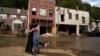 Resident Anne Schneider, right, hugs her friend Eddy Sampson as they survey damage left in the wake of Hurricane Helene, in Marshall, North Carolina, Oct. 1, 2024.