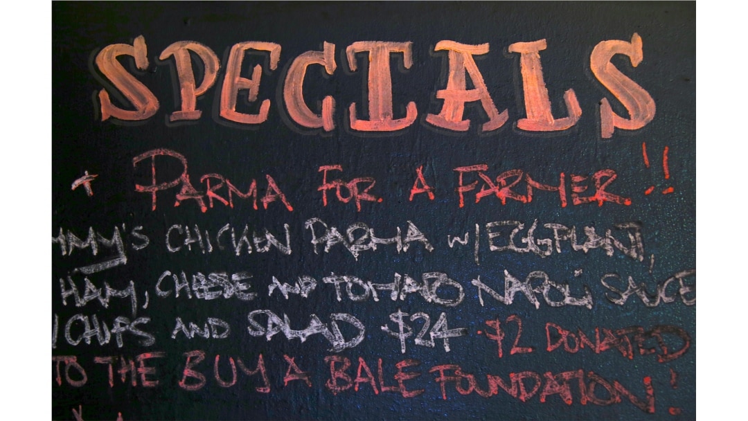 FILE - A menu board at Sydney's Old Fitzroy Hotel displays the slogan 'Parma for a Farmer', meaning that sales of the dish will result in proceeds going to farmers in Australia's parched interior for drought relief, in Sydney, Aug. 9, 2018.