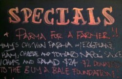 FILE - A menu board at Sydney's Old Fitzroy Hotel displays the slogan 'Parma for a Farmer', meaning that sales of the dish will result in proceeds going to farmers in Australia's parched interior for drought relief, in Sydney, Aug. 9, 2018.