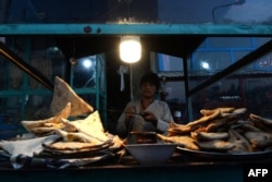 FILE - A young Afghan street vendor prepares bolani (fried bread stuffed with potatoes) at his stall in Mazar-i-Sharif, July 14, 2018.