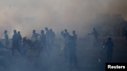 Palestinians react to tear gas fired by Israeli troops during a protest at the Israel-Gaza border in the southern Gaza Strip, July 13, 2018. 