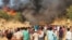 Rohingya refugees watch smoke rising from a fire at the Rohingya refugee camp in Balukhali, southern Bangladesh, March 22, 2021.