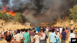 Rohingya refugees watch smoke rising following a fire at the Rohingya refugee camp in Balukhali, southern Bangladesh, March 22, 2021.