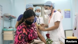 FILE - A healthcare worker holding a rose receives an AstraZeneca vaccine, during the coronavirus disease (COVID-19) vaccination campaign, at a medical center in Mumbai, India, January 16, 2021.
