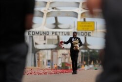 Un hombre riega pétalos en el puente Edmund Pettus antes de que el ataúd del legislador John Lewis fuera llevado por el puente en una procesión en su honor, el domingo 26 de julio de 2020.