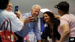 Democratic presidential candidate Joe Biden takes a selfie with a supporter during a campaign event at an electrical workers union hall, July 20, 2019, in Las Vegas.