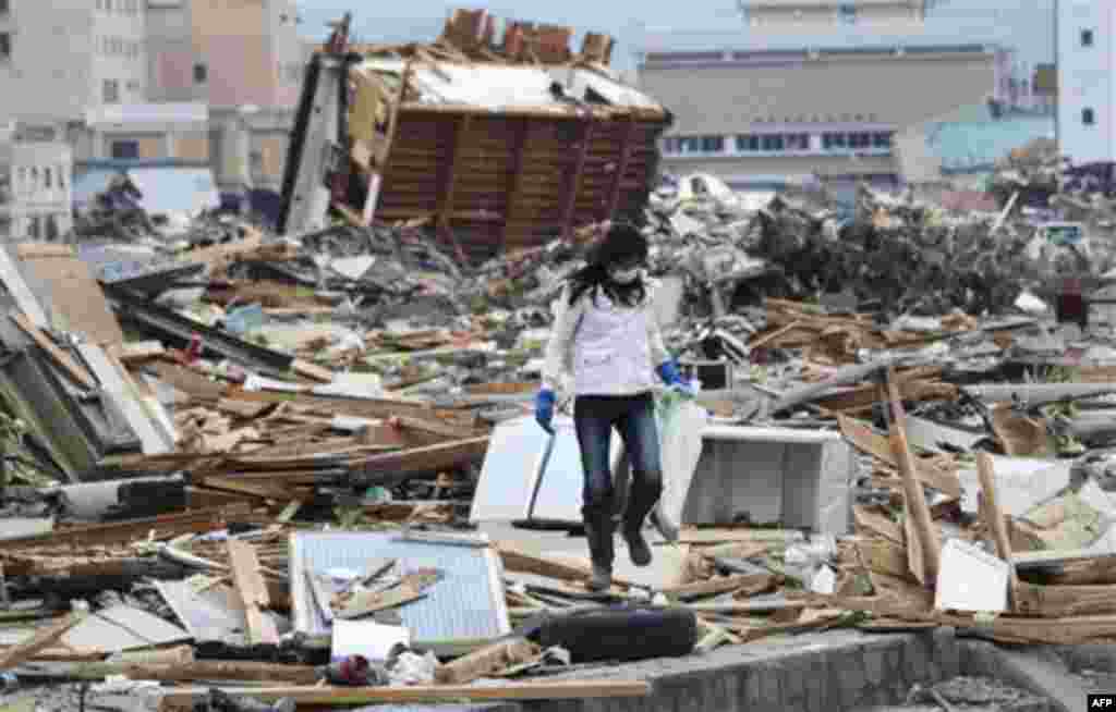 A woman looks for her father-in-law's "ihai" spirit tablet, a placard to designate his seat in a house, in Ofunato, northern Japan, Monday, March 14, 2011, three days after a powerful earthquake-triggered tsunami hit the country's east coast. (AP Photo/Th