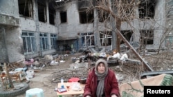 Seorang perempuan lansia memasak makanan di antara puing-puing bangunan di kota Mariupol, Ukraina yang porak-poranda akibat perang (foto: ilustrasi). 