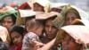 FILE - A Bangladeshi woman shields her baby from the sun as she stands in a line at a rice shop in Dhaka, April 5, 2008.