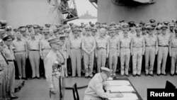 FILE - General Douglas MacArthur signs as Supreme Allied Commander during Japan's formal surrender ceremonies on the battleship USS Missouri in Tokyo Bay, Sept. 2, 1945. (Lt. C. F. Wheeler/US Navy/Handout via Reuters)