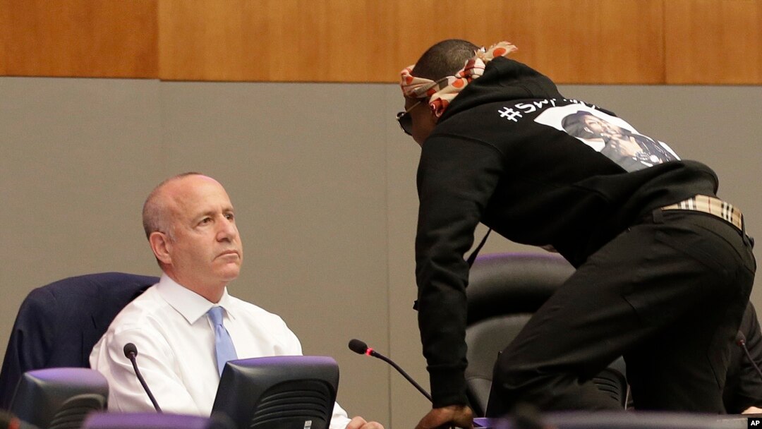 Stevante Clark jumps on the dais and shouts at Sacramento Mayor Darrell Steinberg, left, during a city council meeting in Sacramento, California, March 27, 2018. 