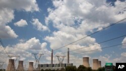 FILE — A coal truck, right, passes the coal-powered Duvha power station, near Emalahleni (formerly Witbank) east of Johannesburg, Thursday, Nov. 17, 2022. 