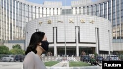 北京的中国人民银行总部大楼前，有人戴口罩走过（2018年9月28日）。