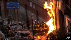 Fire-fighters carry a dead body next to a damaged building at Toledo Street following an explosion in downtown Madrid, Spain, Jan. 20, 2021.