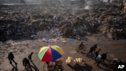 Palestinos pasan junto a montones de basura ardiendo en la Ciudad de Gaza, que no cuenta con sistema de recogida de basuras, el 12 de febrero de 2025