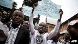 Des Congolais brandissent des pancartes lors d'une manifestation après un service catholique pour commémorer les victimes de la répression de la marche du mois dernier à l'extérieur d'une cathédrale à Kinshasa, le 12 janvier 2018.