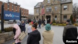 Customers wait in line outside a branch of the Silicon Valley Bank in Wellesley, Massachusetts, March 13, 2023.