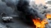 Iraqi demonstrators burn tires as they block the road during ongoing anti-government protests, in Baghda.