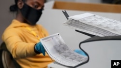 A county election worker scans mail-in ballots at a tabulating area at the Clark County Election Department, Thursday, Nov. 5, 2020, in Las Vegas. (AP Photo/John Locher)