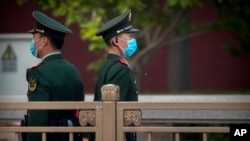 Chinese paramilitary police wearing face masks to prevent the spread of the new coronavirus stand guard along a street near Tiananmen Square in Beijing on April 29, 2020. 