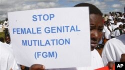FILE - A Masai girl holds protest sign during an anti-Female Genital Mutilation (FGM) run in Kilgoris, Kenya.