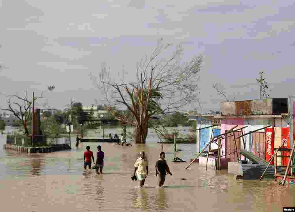 Para warga mengarungi jalanan yang banjir setelah Topan Phailin menghantam Gopalpur distrik Ganjam di negara bagian Odisha di timur India (13/10). (Reuters/Ahmad Masood)