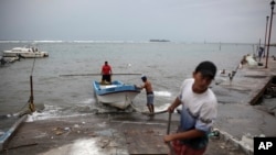 FILE - Fishermen drag a boat onto dry land to protect it ahead of the arrival of Tropical Storm Franklin, in the port city of Veracruz, Mexico, Aug. 9, 2017.