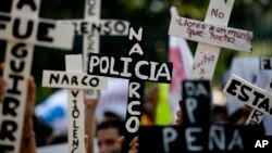 FILE - Demonstrators march with crosses with writing that reads in Spanish "Narco Cops" in protest for the disappearance of 43 students in the state of Guerrero, in Mexico City, Nov. 5, 2014.