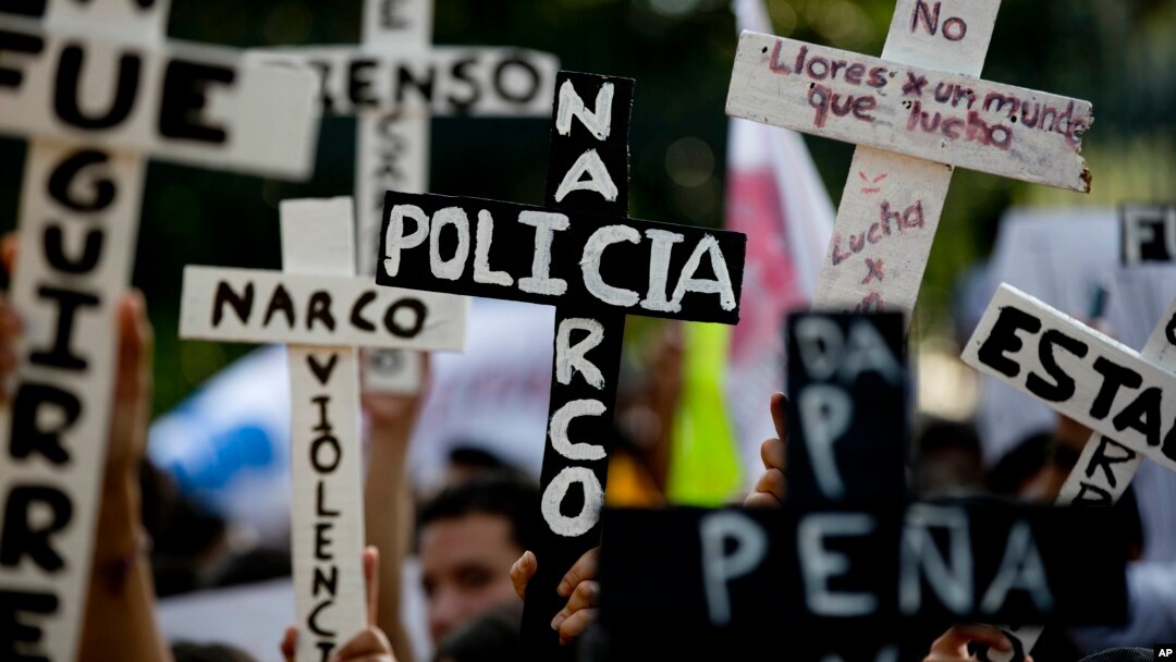 Demonstran membawa salib bertuliskan "Polisi Narkoba" dalam protes yang menuntut ditemukannya 43 mahasiswa yang diculik, di Guerrero, Mexico City (5/11). (AP/Eduardo Verdugo)