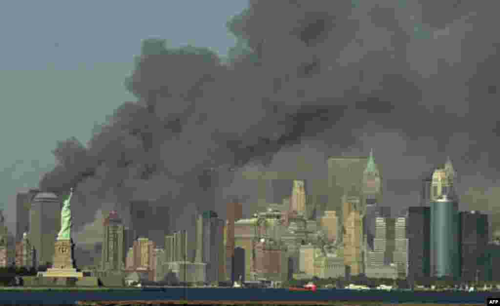 Thick smoke billows into the sky from the area behind the Statue of Liberty, lower left, where the World Trade Center towers stood, on Tuesday, Sept. 11, 2001. The towers collapsed after terroists crashed two planes into them. (AP Photo/Daniel Hulshizer)