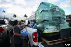 Volunteers load pallets of supplies and aid donations flown in from the Hawaiian island of Kauai into pickup trucks at the Kahului airport cargo terminal in the aftermath Maui wildfires in Kahului, Hawaii on August 13, 2023. (Photo by Patrick T. Fallon / AFP)