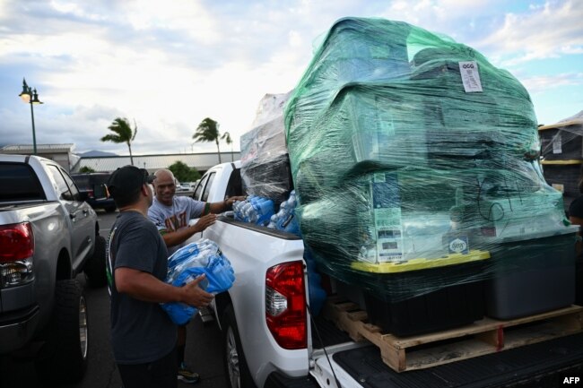 Volunteers load pallets of supplies and aid donations flown in from the Hawaiian island of Kauai into pickup trucks at the Kahului airport cargo terminal in the aftermath Maui wildfires in Kahului, Hawaii on August 13, 2023. (Photo by Patrick T. Fallon / AFP)