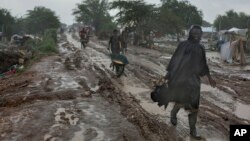 FILE - People trudge along the main passageway through United Nations' Malakal Camp for Internally Displaced People, (IDP) during the wet season which has made life for hundreds of thousands of IDPs in South Sudan very challenging, in Malakal, Sudan.