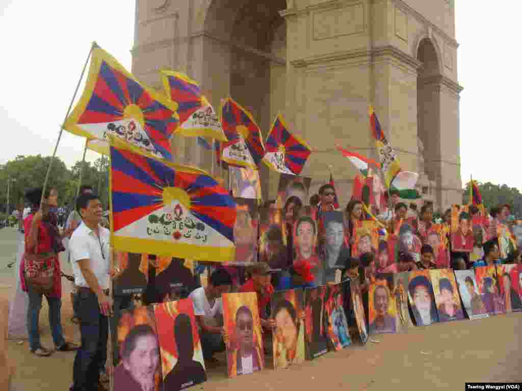 Exile Tibetans hold photos of those who self immolated for the cause of Tibet during a candle light vigil near the India Gate monument, in background, in New Delhi, India, Wednesday, July 25, 2012. (VOA Photo/Delhi Stringer Tsering Wangyal)