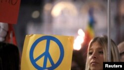 Seorang perempuan memegang poster yang bermakna kedamaian dalam aksi demo menentang invasi Rusia di Ukraina di Venesia, Italia, pada 2 Maret 2022. (Foto: Reuters/Manuel Silvestri)