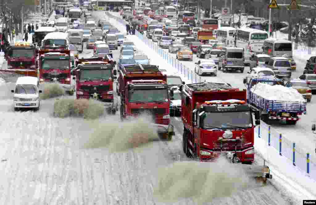 Truk-truk pembersih salju membersihkan jalanan di kota Harbin, provinsi Heilongjiang, China.