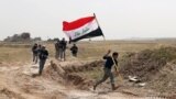 A member of the Iraqi security forces runs to plant the national flag during clashes to regain Tikrit from Islamic State militants.