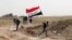A member of the Iraqi security forces runs to plant the national flag during clashes to regain Tikrit from Islamic State militants.