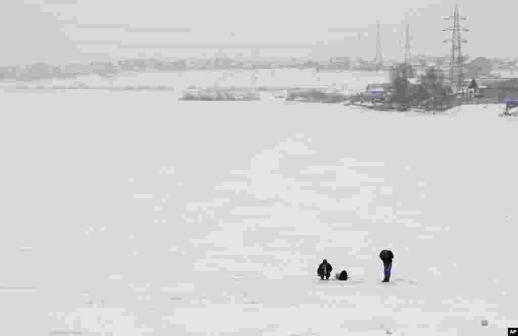 Two men fish on a frozen lake near Bucharest February 2, 2012. (Reuters)