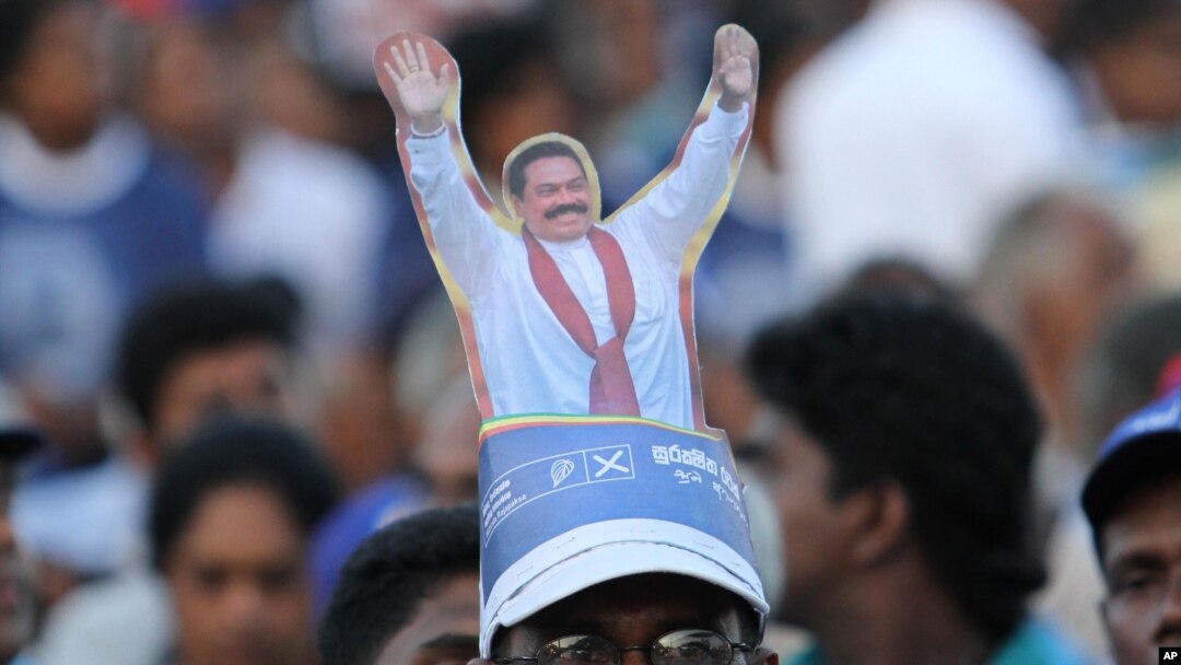 Topi berbentuk Presiden Sri Lanka Mahinda Rajapaksa yang dipakai seorang pendukungnya dalam kampanye pilpres di Kesbewa, sekitar 20 kilometer dari Kolombo, Sri Lanka (5/1). (AP/Sanka Gayashan)