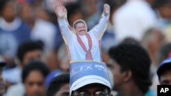 Topi berbentuk Presiden Sri Lanka Mahinda Rajapaksa yang dipakai seorang pendukungnya dalam kampanye pilpres di Kesbewa, sekitar 20 kilometer dari Kolombo, Sri Lanka (5/1). (AP/Sanka Gayashan)