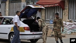 Yemeni army soldiers, check a car, at a checkpoint in Sana'a, June 11, 2011