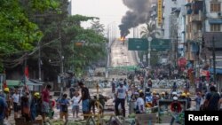 Para pengunjuk rasa antikudeta berjalan di balik barikade sementara api berkobar di jembatan Bayint Naung di Mayangone, Yangon, Myanmar, 16 Maret 2021. REUTERS/Stringer