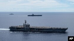 ARCHIVO - En esta foto proporcionada por la Marina de los EE. UU., los grupos de ataque del portaaviones USS Ronald Reagan (CVN 76, frente) y USS Nimitz (CVN 68, parte trasera) navegan juntos en formación, en el Mar de China Meridional, el 6 de julio de 2020.