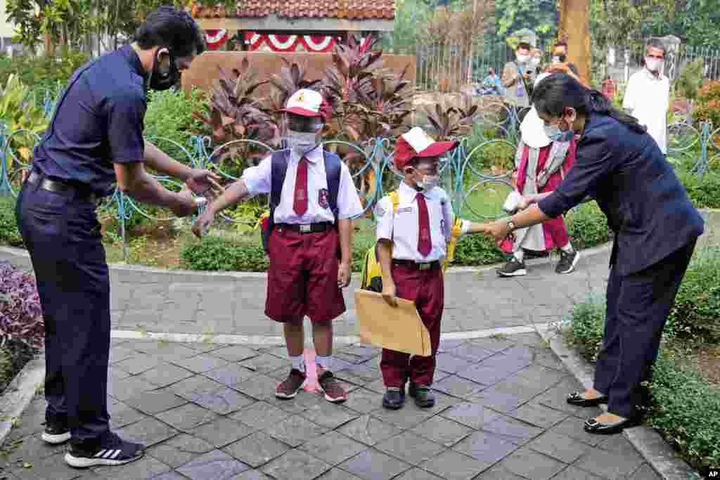 Para guru memeriksa suhu tubuh siswa Sekolah Dasar pada hari pertama pembukaan kembali sekolah di Jakarta, Indonesia, Senin, 30 Agustus 2021. (Foto: AP / Dita Alangkara)