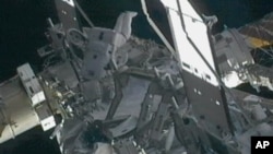 Space station commander Sunita Williams (C) works on a leaky radiator system just hours after being hit by a piece of orbiting debris, outside the International Space Station, November 1, 2012.