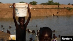 Seorang anak mengangkat ember yang berisi air di dekat kamp penampungan pengungsi PBB di Bentiu, Negara Bagian Unity, Sudan Selatan (17/6/2014).