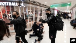 An undercover policeman points a can of pepper spray as others detain a protester during a demonstration at a shopping mall popular with traders from mainland China near the Chinese border in Hong Kong, Dec. 28, 2019. 