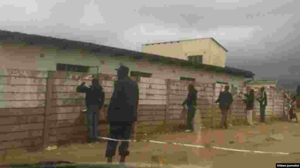 The day before the election, Zanu-PF supporters tear down MDC posters while a police officer watches.